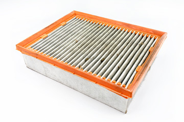 Worn and dirty rectangular car air filter, visible leaves and dirt, isolated on white background with a clipping path, upper filter side visible.
