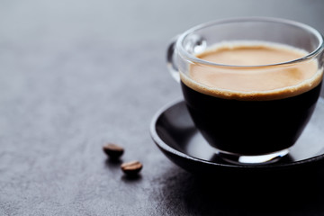Coffee in glass cup on dark stone background. Close up.	