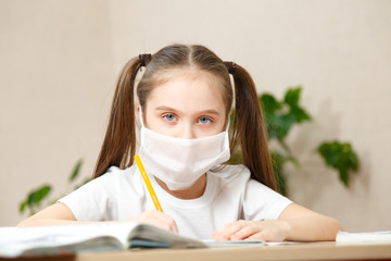 Distance learning online education. schoolgirl in medical mask studying at home,