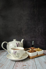 Obraz na płótnie Canvas Mug with red tea, teapot and dry tea leaves. Dark background with copyspace