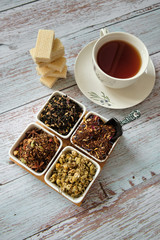 Top view of a mug with red tea, dry tea leaves and wafer biscuits
