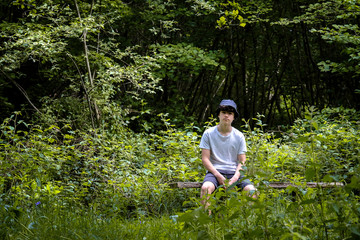 Naklejka na ściany i meble A teenage boy sits in the woods wearing a Barbour hat in Suffolk England.