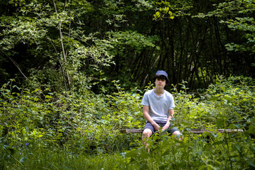 A teenage boy sits in the woods wearing a Barbour hat in Suffolk England.