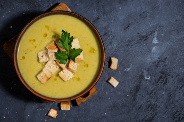 broccoli cream soup with croutons in a bowl on dark background