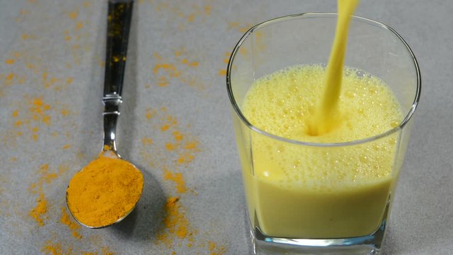 Serving turmeric milk also called as Golden Milk in a glass cup garnished with cinnamon powder