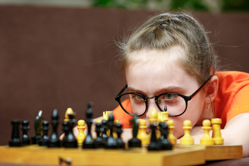 Portrait Caucasian Little girl playing chess at home during quarantine. Early childhood development