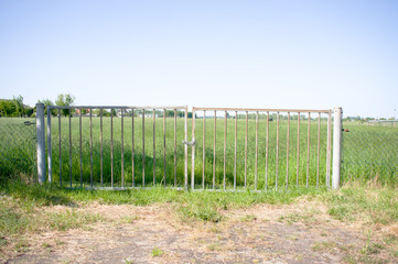 Fototapeta na wymiar Closed gate that gives access to a path to a green meadow