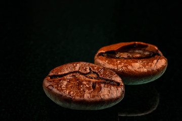 a coffee beans macro shot with water drops and reflection. Black background