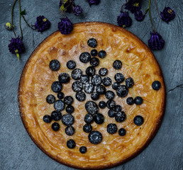Home made white chocolate cake, decorated with blueberries on a black plate. 