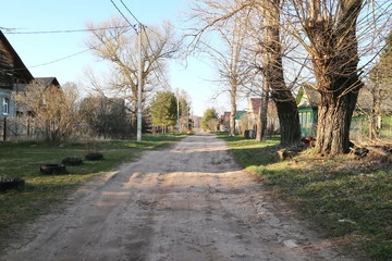 Dirt road in spring sunny evening in the village