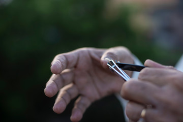 man cutting his nails by a nail cutter on rooftop outdoor. Covid, Lock down and Home isolation