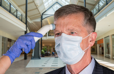 Fototapeta na wymiar Mockup of shopping mall with senior adult wearing mask having a fever or temperature test taken to check coronavirus status