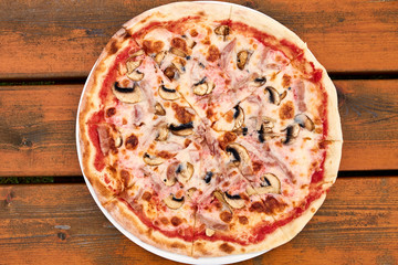 A ham and mushroom pizza sitting on top of a wooden table