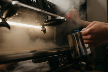 Fototapeta na wymiar A close photo of a professional coffee machine. A barista steams a metal mug.