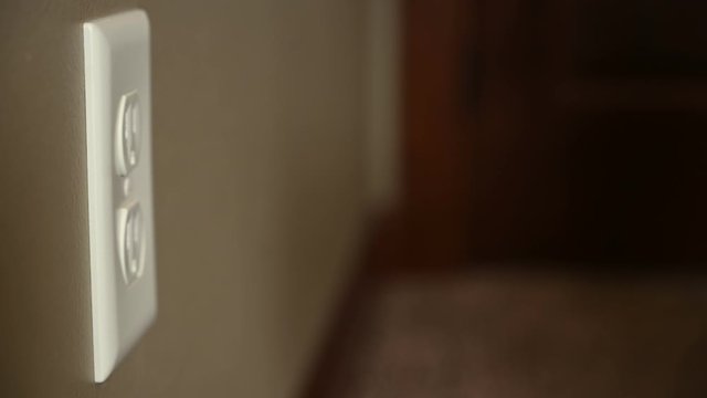 Side view of Caucasian hand unplugging an electrical outlet