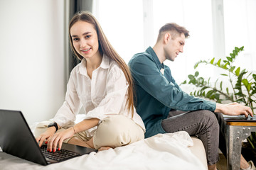 young and beautiful caucasian couple use laptop, work at home, man and woman busy with their own business. couple at freelance work