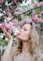 Fototapeta premium Beautiful blond girl sniffing flowers in the garden.