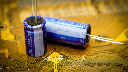 Electronic capacitor on a golden printed circuit board - obrazy, fototapety, plakaty