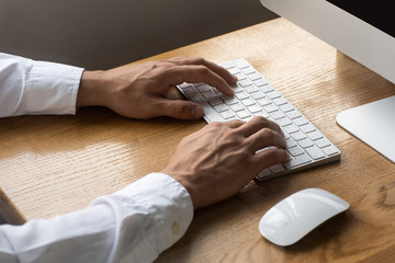 Men's hands, keyboard and mouse on the wooden table