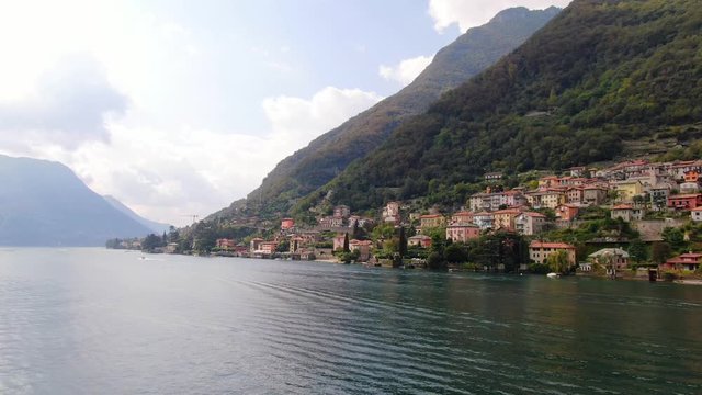 The small beautiful Italian city of Laglio resort. One of the villas is owned by the famous Hollywood actor George Clooney. Aerial view from the side of Lake Como. Drone shooting on a summer day