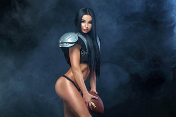 American football. Young sporty brunette wearing sexy uniform of rugby football player posing with...