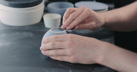 Fototapeta na wymiar man hands polishing bottom of blue ceramic cup