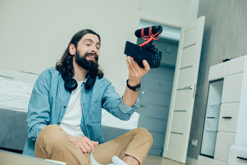 Positive man recording himself on the camera and smiling cheerfully
