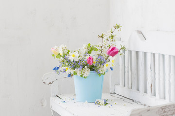 spring flowers in vintage white interior with old wooden bench