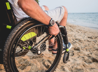 Disabled man in a wheelchair on the beach.