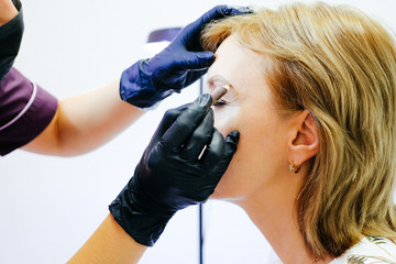 Close Up of Esthetician Filling in Eyebrows of Female Client with Dark Brown Make Up During Eyebrow Spa Treatment.