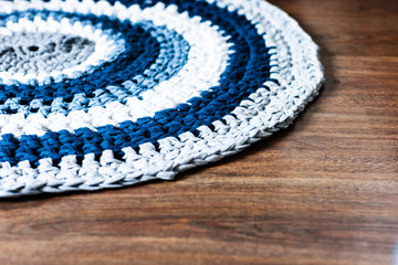 handmade round wicker rug on a wooden floor, cozy home interior decor in blue, gray and white colors.