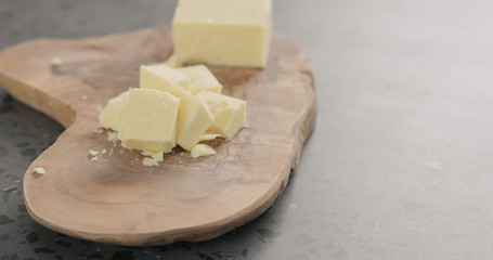 cheddar cheese in cubes on olive wood board