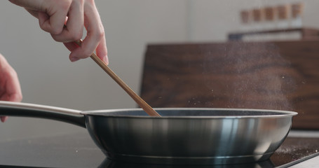 man hand moving something with wooden spatula in fry pan