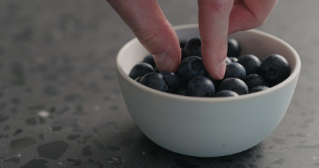 man hand take ripe blueberries in white bowl closeup