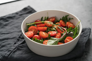 salad with cherry tomatoes and mixed grens in white bowl on concrete background