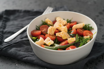 salad with cherry tomatoes, mixed grens and cheese in white bowl on concrete background