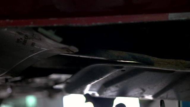 Mechanic uninstalling old car details. Close up male hands disassemling parts of lifted car.