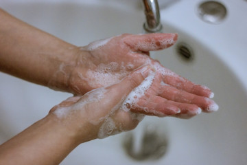 To prevent a coronavirus pandemic, a girl washes her hands with soap and water, proper washing and...
