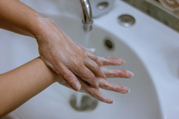 To prevent a coronavirus pandemic, a girl washes her hands with soap and water, proper washing and handling of an antiseptic will protect against the virus.