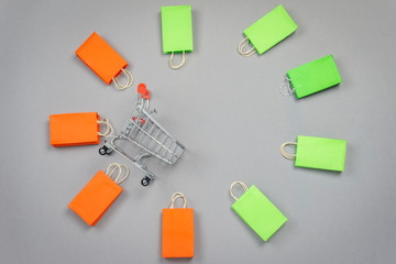Fototapeta na wymiar empty shopping basket with colorful shopping bags lay on grey background. shopping concept