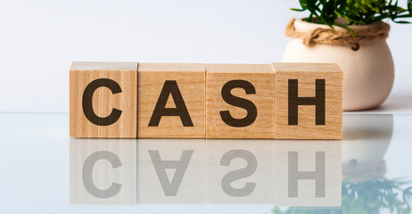 Letter block in word cash on wood background. wooden background. The inscription is reflected from the glass surface. Front view.