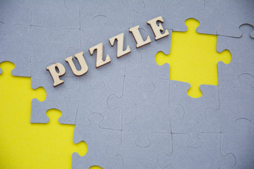 Missing jigsaw puzzle piece on yellow background. Label PUZZLE on top. Home Board game concept.
