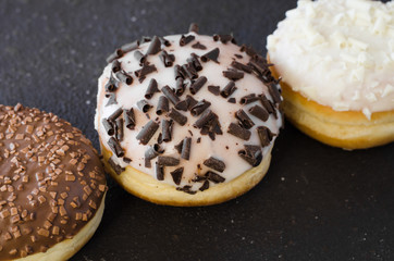 Traditional donut day. Assorted donuts with chocolate glazed on concrete background.