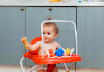 happy baby sitting in red walkers and eating a cracker. baby smiling