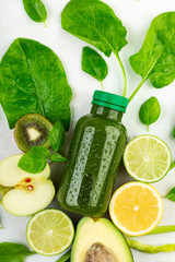 Vertical frame of freshly blended smoothie crreatively surrounded by the ripe fruits and vegetables from which it is made on white background. Beverage manual concept