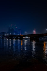 Fototapeta na wymiar Moody foggy London night scene of bridge and lights reflected at night