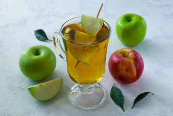 Apple juice in a glass and a few ripe apples on a light blue surface. Concept healthy eating, healthy lifestyle. Selective focus, horizontal orientation.