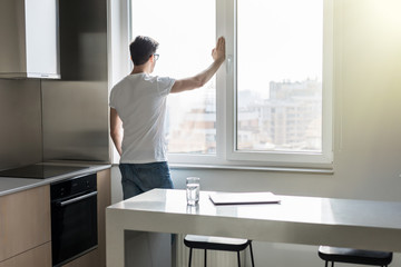 Young man looking out the window in the kitchen