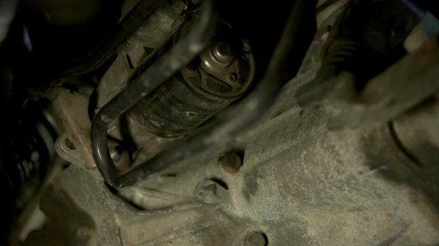 Close up mechanic man unscrewing car cylinder. Repairman uninstalling old car detail.