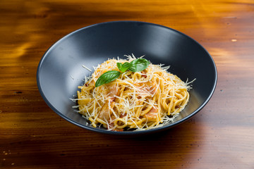 Spaghetti Carbonara with bacon on wooden table